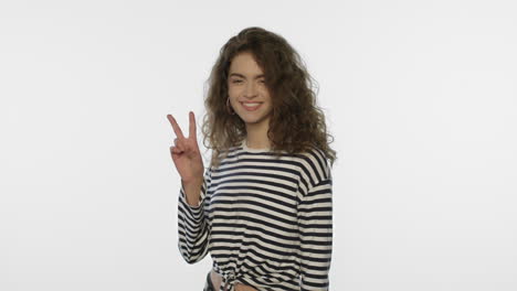 mujer sonriente mostrando el signo v en fondo blanco. chica positiva muestra el gesto v
