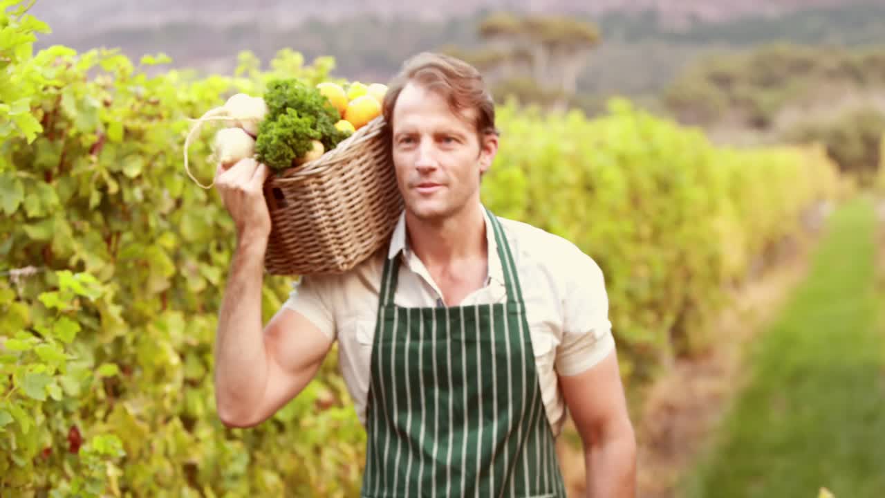 joven agricultor feliz sosteniendo una canasta de verduras