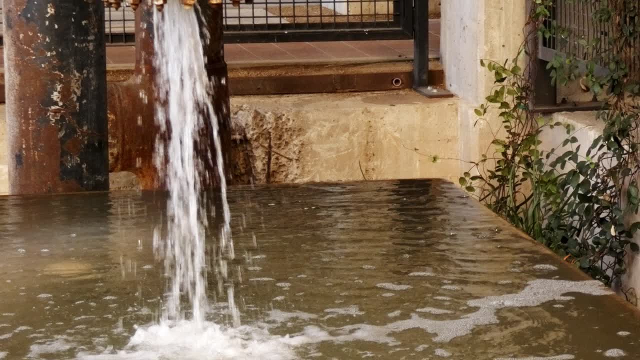 el agua sale a borbotones de la vieja tubería oxidada al tanque de agua para el mantenimiento