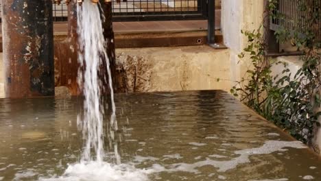 water gushing out of old rusty pipe into water tank for maintenance