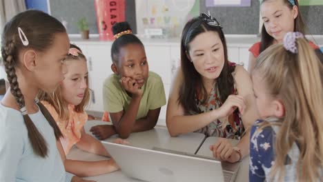 Happy-diverse-female-teacher-and-schoolgirls-using-laptop-in-elementary-school-class,-slow-motion