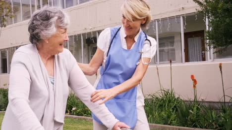 Female-nurse-assisting-a-senior-woman-to-walk