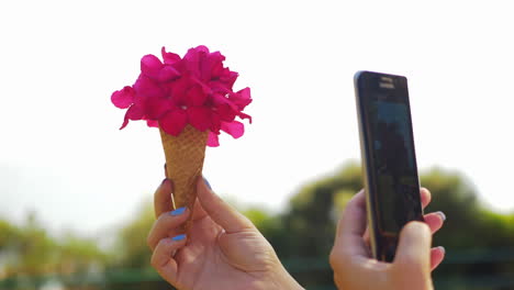 mujer con móvil tomando una foto de un ramo de flores de cono