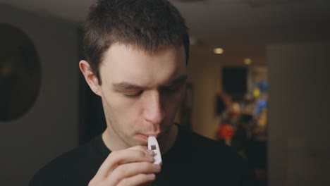 sick man puts thermometer in mouth - medium shot