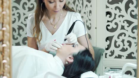 a female beautician holds a permanent lip makeup tattoo machine. beauty saloon