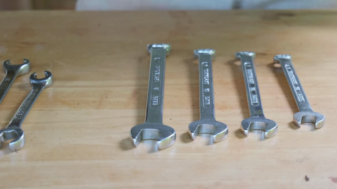 Man cleaning and arranging hand tools on a wooden bench, clip 1