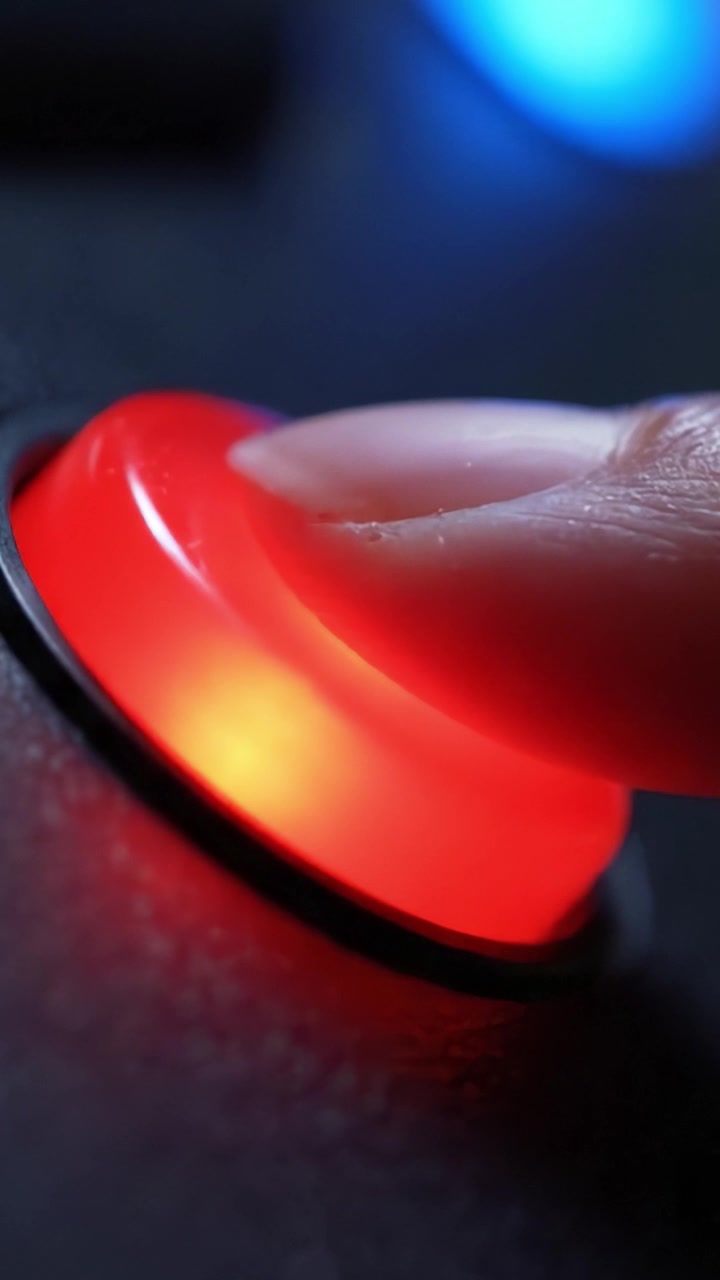 Primo piano su un pulsante rosso illuminato con un bagliore vivido che esalta la texture della superficie, su uno sfondo scuro con accenti di luce blu