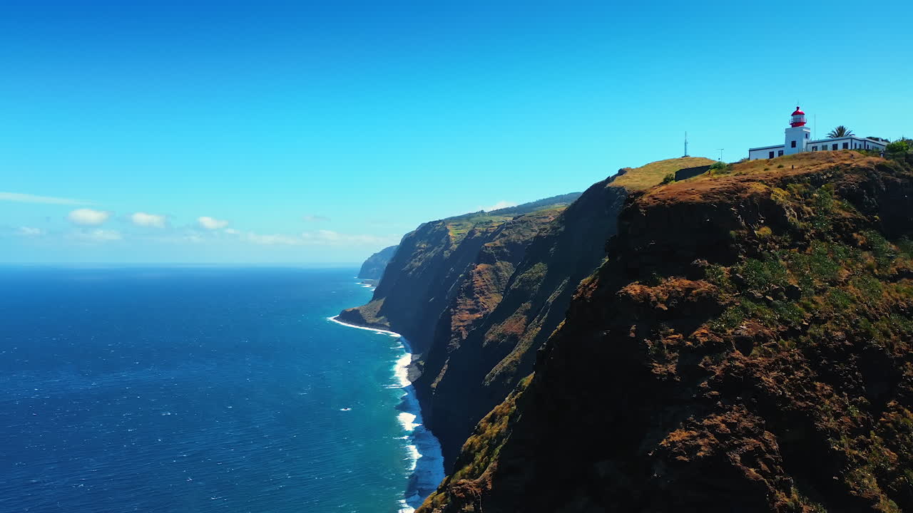 A lighthouse located on the high rock at the waterscape of the Atlantic Ocean. Mountainous coast of the Madeira Islands, Portugal.