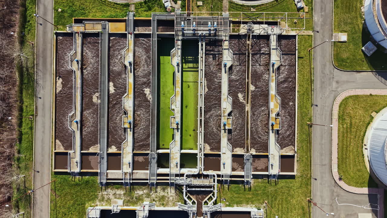 Water treatment facility processes wastewater with multiple treatment lines and large aeration tanks in daylight