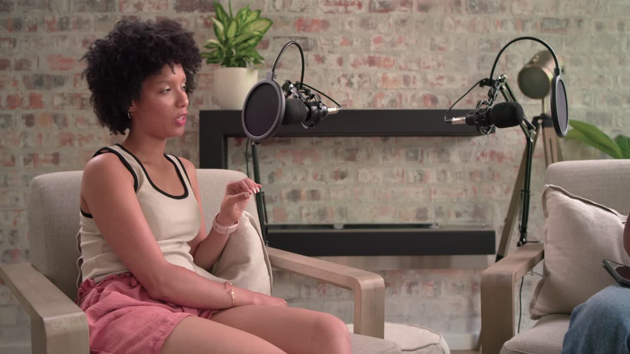 Women in studio host looking and adjusting tablet guest counting and speaking podcasting with mics
