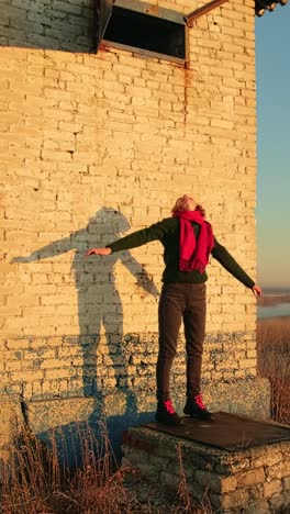 woman enjoying sunrise by a rustic building