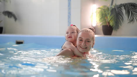 healthy family mother teaching baby swimming pool