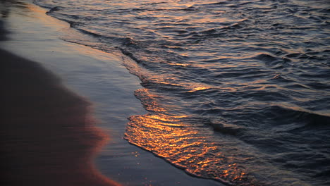 waves lightly crashing on beach during sunset