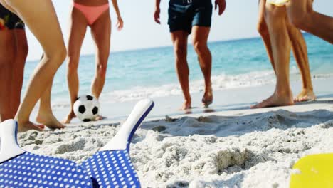 sección baja de amigos jugando al fútbol en la playa