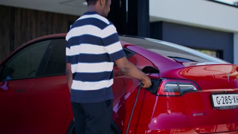 man charging electric vehicle at home