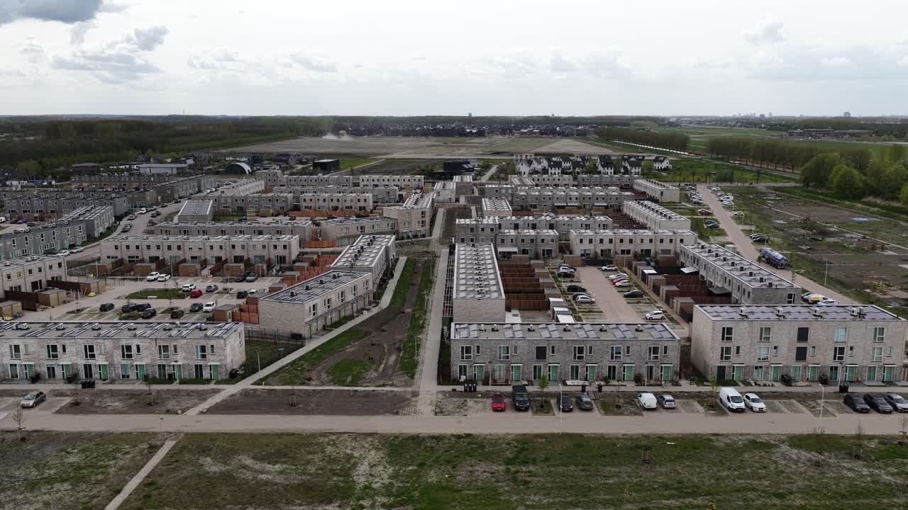 Aerial perspective revealing a sprawling new residential neighborhood with rows of modern houses under construction, showcasing the development and expansion of a suburban community