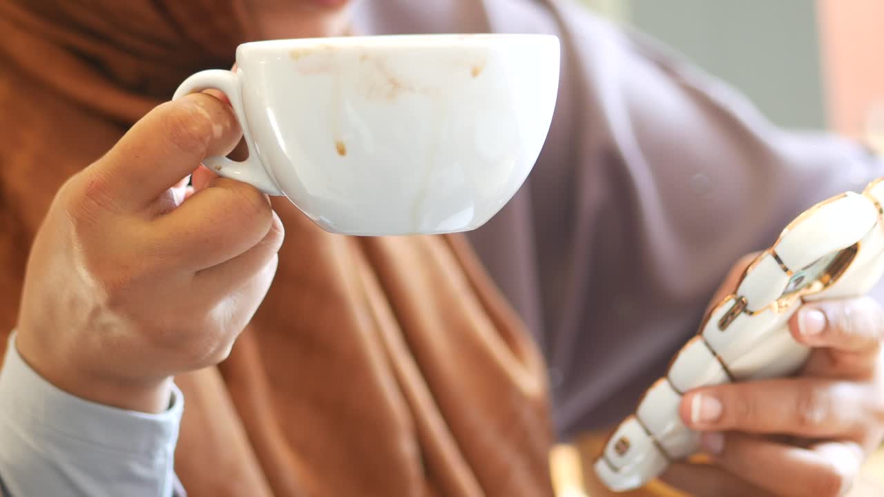 Woman drinking coffee and using a smartphone in a cafe