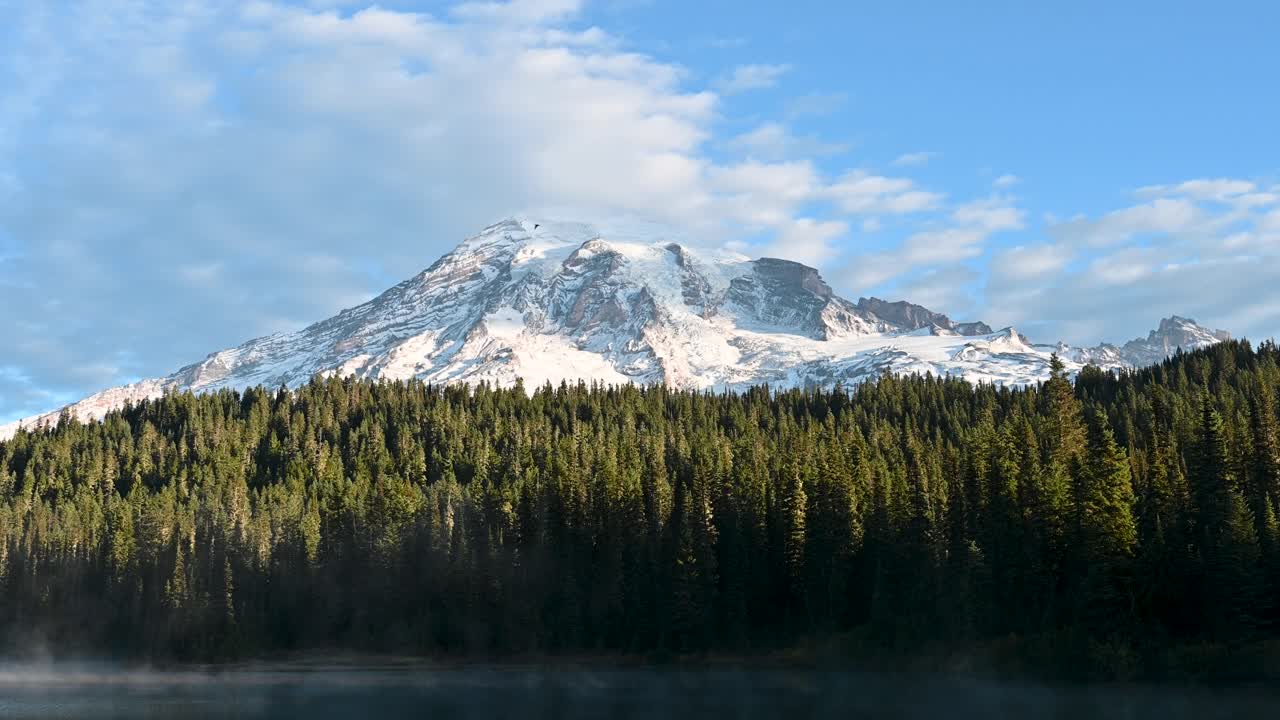 Mount Rainier mountaintop, sunlit forest and refletive lake