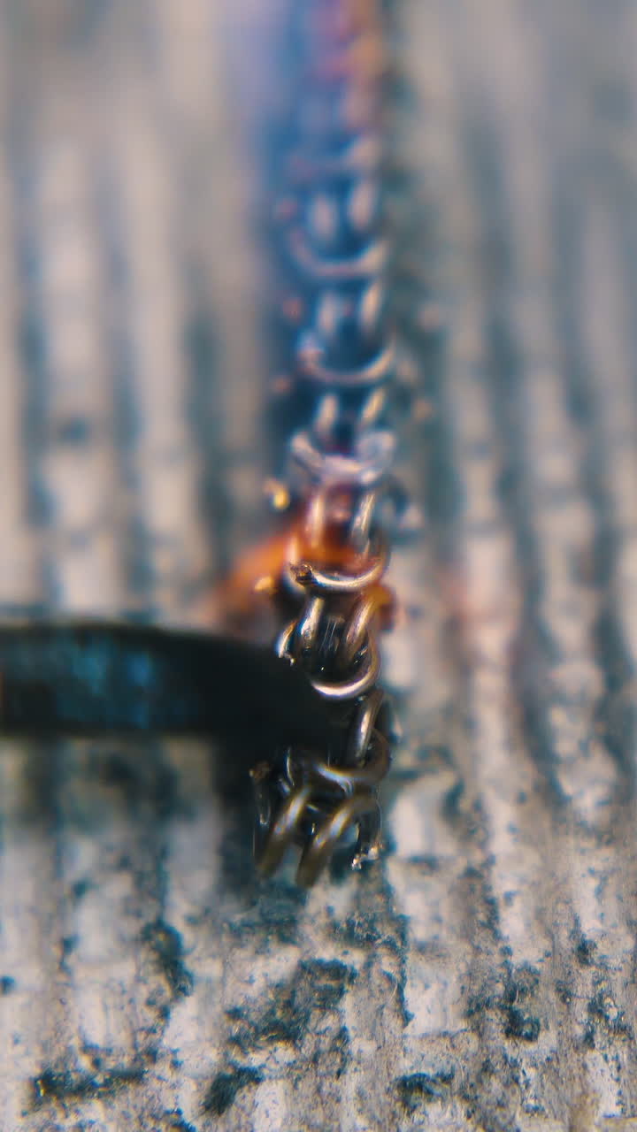 CU shot: worker uses thin brush to descale part of heated gold chain with special material on asbestos sheet extreme closeup