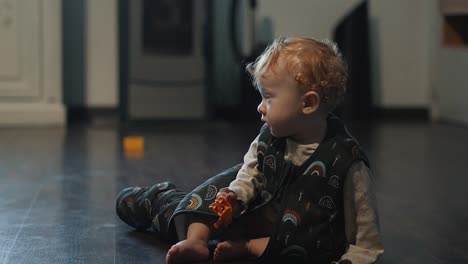 little baby girl in sleeping bag playing with some toys on the living room floor