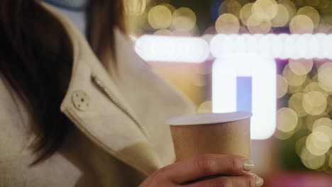 detalle del video de una mujer sosteniendo una taza de vino caliente humeante