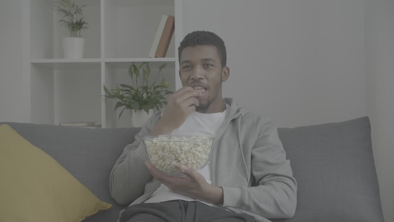 영화를 즐기고 팝콘을 먹는 젊은 아프리카계 미국인 남자