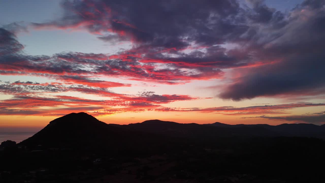 Stunning twilight view with colorful clouds over dark mountain silhouette