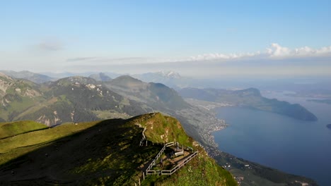 Sobrevuelo-Aéreo-Sobre-Niederbauen-Chulm-En-Uri,-Suiza-Con-Vistas-Al-Lago-De-Lucerna-Con-Vistas-A-Pilatus,-Burgenstock-Y-Los-Acantilados-De-La-Cumbre-Con-Un-Excursionista-En-El-Mirador