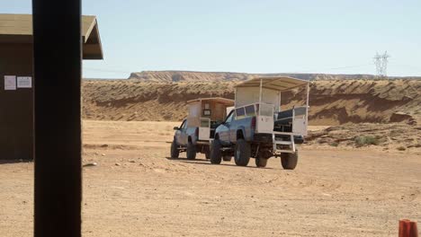 tiro de paisaje de mano de dos camionetas levantadas construidas con asientos para turistas para conducir a través del desierto de arizona naranja seco para visitas con guías en un cálido día soleado de primavera