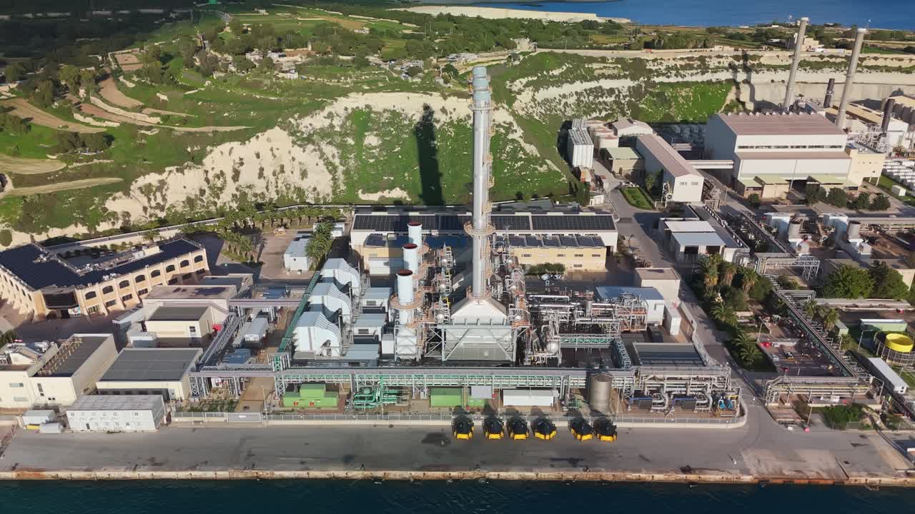 Vista aérea ascendente de la central eléctrica de Delimara en Marsaxlokk, Malta, que destaca la infraestructura industrial, los paisajes costeros y las modernas instalaciones energéticas con el Mediterráneo como telón de fondo