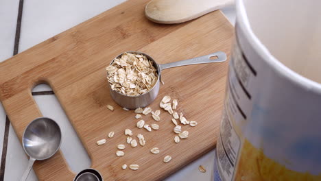 a pile of oat grain cereal with kitchen utensils and a measuring cup for a healthy and nutritious oatmeal breakfast top down