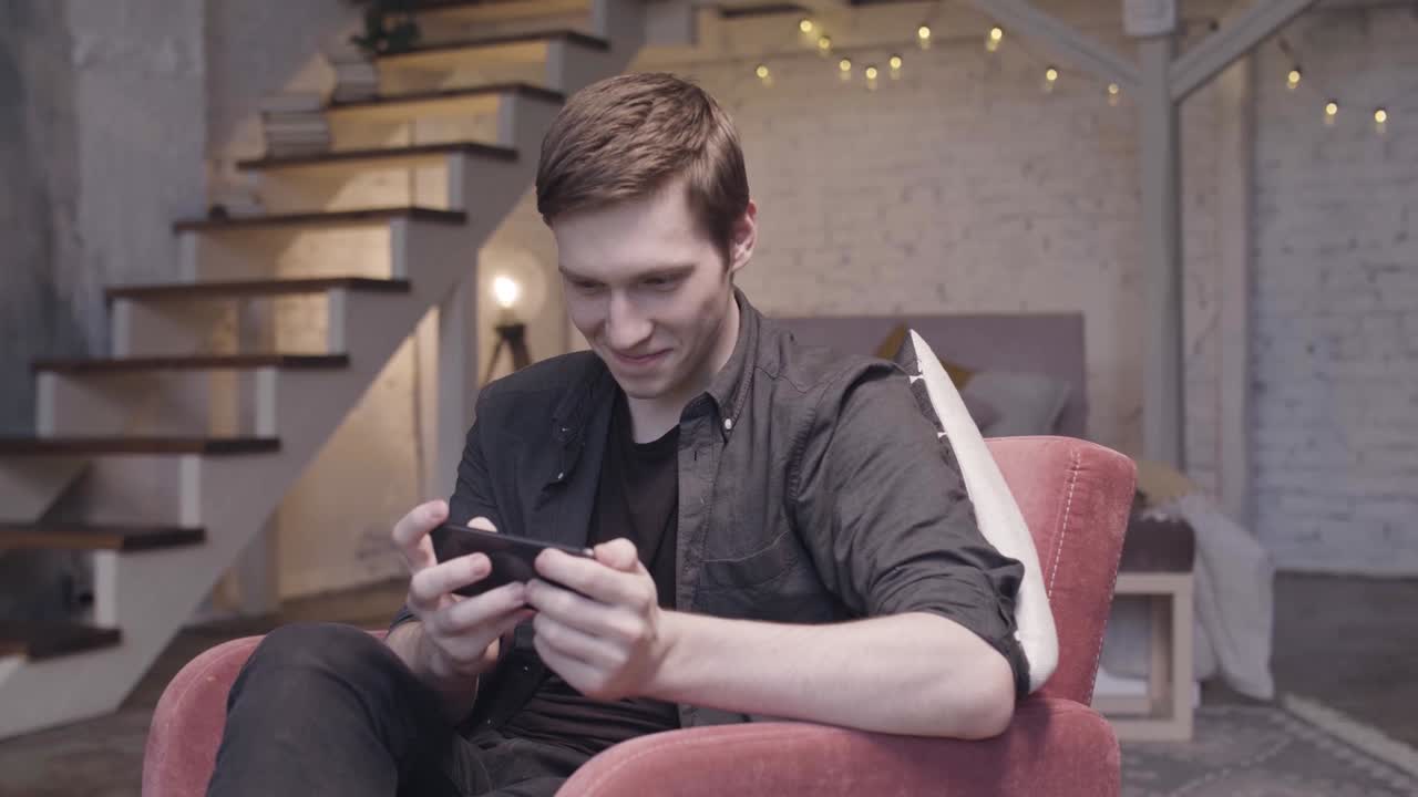 집에서 스마트폰으로 게임을 하는 젊은 남자