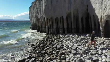 vista aérea de una mujer solitaria caminando en la costa rocosa del lago crowley por columnas, maravilla natural y punto de referencia escénico de california usa