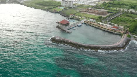 drone shot over the blue waters crashing with the wave breaker and lighthouse