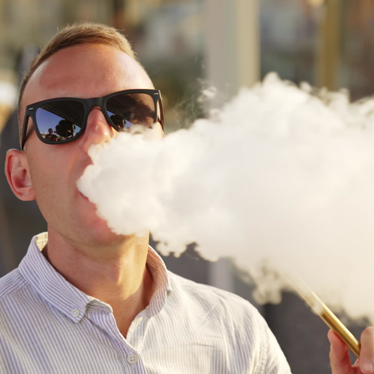 Young man having relaxing time resting in hookah bar. Male in sunglasses smoking shisha close up. Blurred backdrop