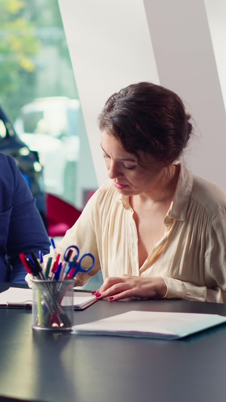 Donna professionista che scrive su documenti durante una riunione di lavoro.