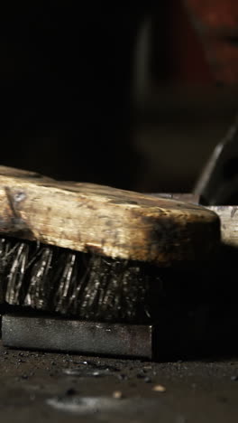 hands of welder using wire brush on a piece of metal