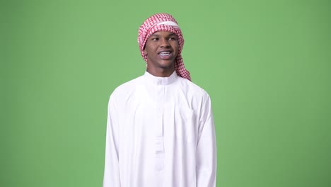 young african man wearing traditional muslim clothes against green background