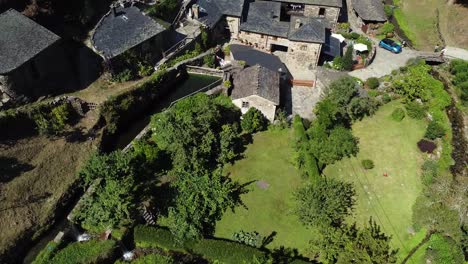 Toma-Aérea,-Drone-Volando-Hacia-Atrás-Desde-Un-Pequeño-Pueblo-En-El-Valle-De-Las-Verdes-Montañas-De-Asturias,-España