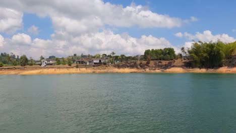 homes along coastline of guatape lake, colombia, view from moving boat 60fps