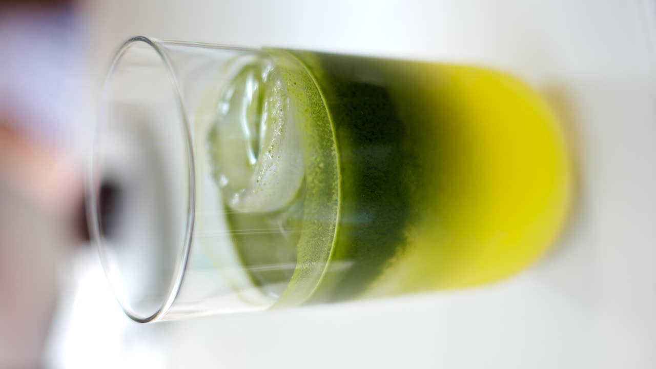 Glass of matcha cocktail with ice close up, vertical screen