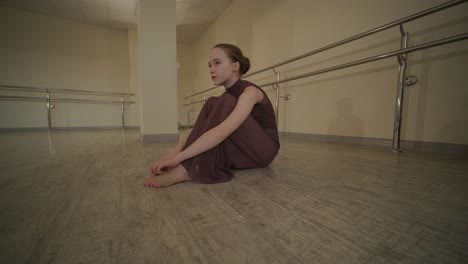 a group of young ballet students in black dancewear practicing positions in a spacious ballet studio with wooden flooring and wall-mounted barres. focused expressions and synchronized movements.