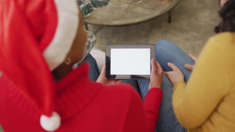 Felices-Y-Diversas-Amigas-Con-Sombreros-De-Papá-Noel-Haciendo-Videollamadas-Navideñas-Con-Tabletas,-Copiando-Espacio-En-La-Pantalla