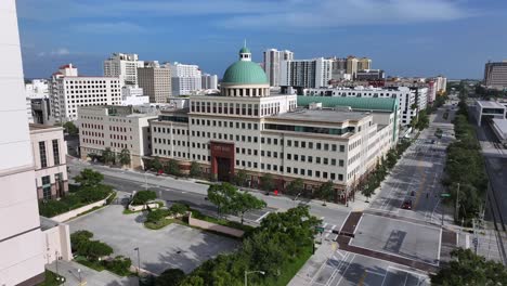 west palm beach city hall stands prominently on an empty street, surrounded by mid-rise buildings