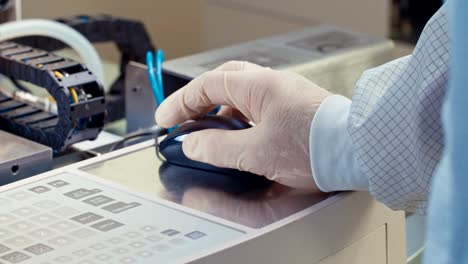 cerca de una mano de trabajador con guante trabajando con un ratón de computadora
