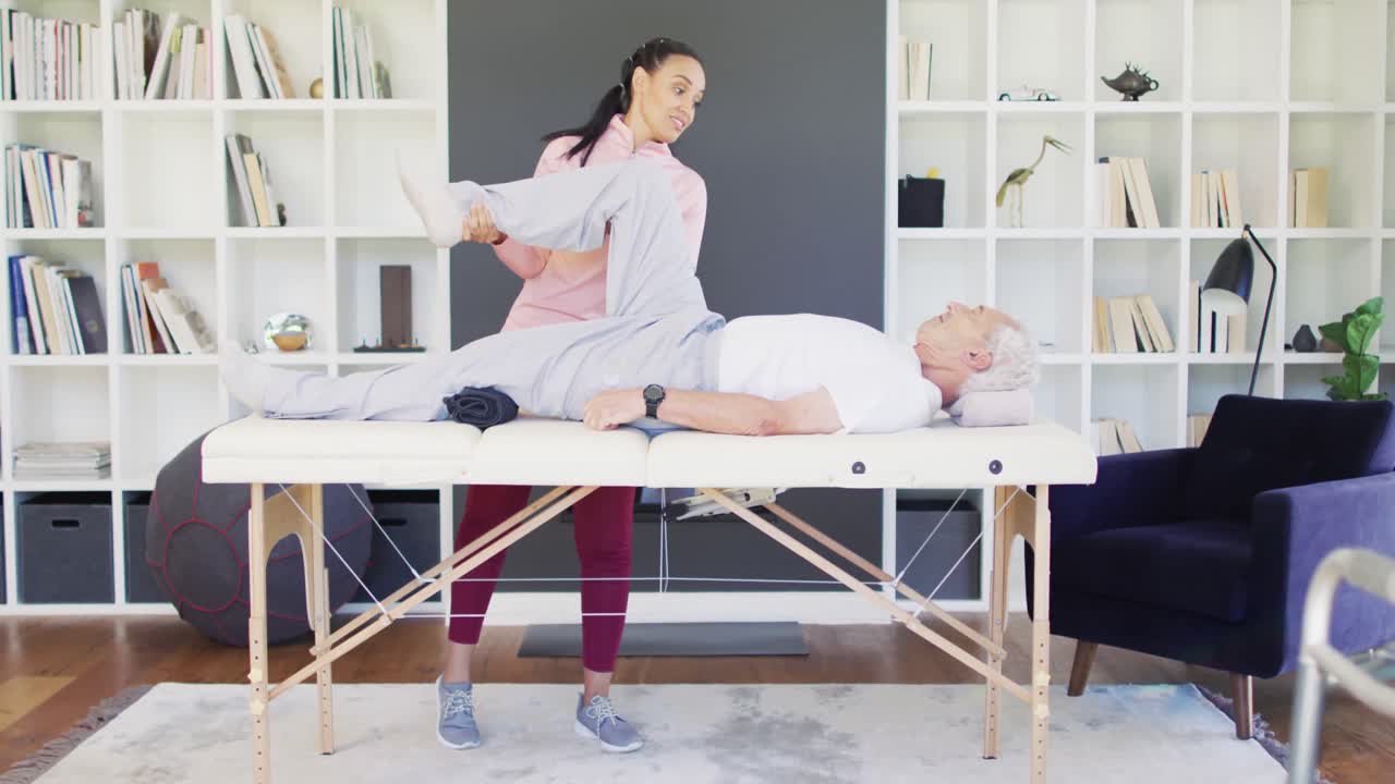 video de una fisioterapeuta bi-racial feliz haciendo ejercicio con un hombre caucásico mayor