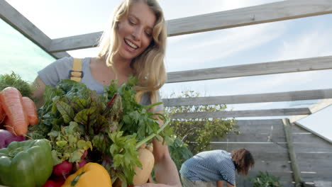 Feliz-Pareja-Diversa-Sosteniendo-Una-Canasta-De-Verduras-Frescas-Y-Trabajando-En-El-Jardín,-Cámara-Lenta