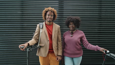 portrait of cheerful african american friends with e-scooters on street