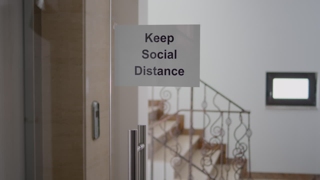 Porta in vetro dell'ufficio con un poster per il distanziamento sociale.
