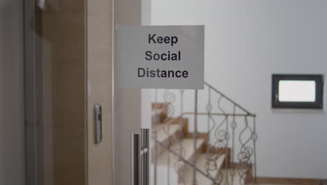 Glass-office-dor-with-keep-social-distance-poster-on-it